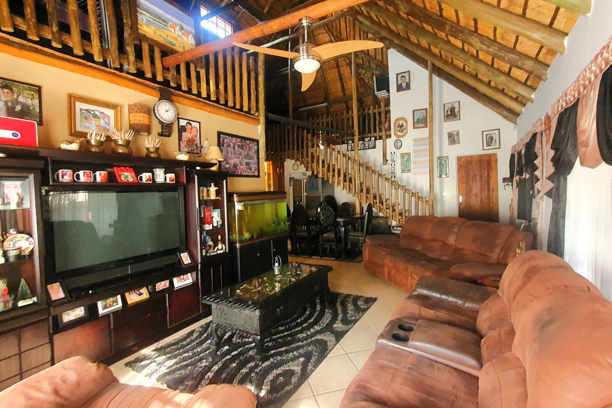 Spacious living area featuring high vaulted ceilings with exposed timber trusses, a mezzanine level, and a wooden staircase.