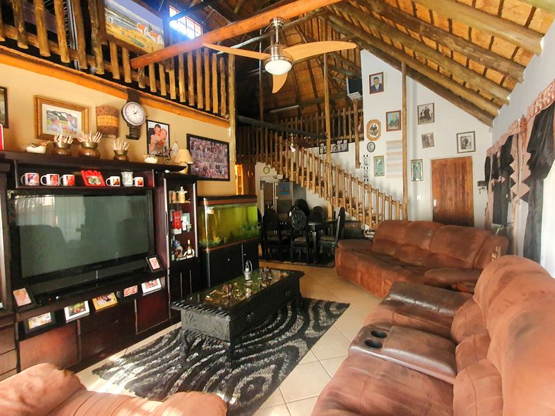 Spacious living area featuring high vaulted ceilings with exposed timber trusses, a mezzanine level, and a wooden staircase.