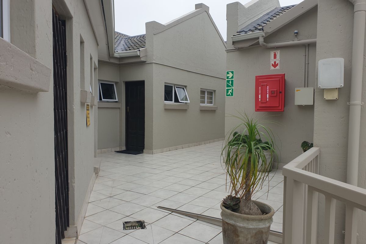 A paved outdoor courtyard area featuring tiled flooring, emergency fire safety equipment, and access points to the apartment building.