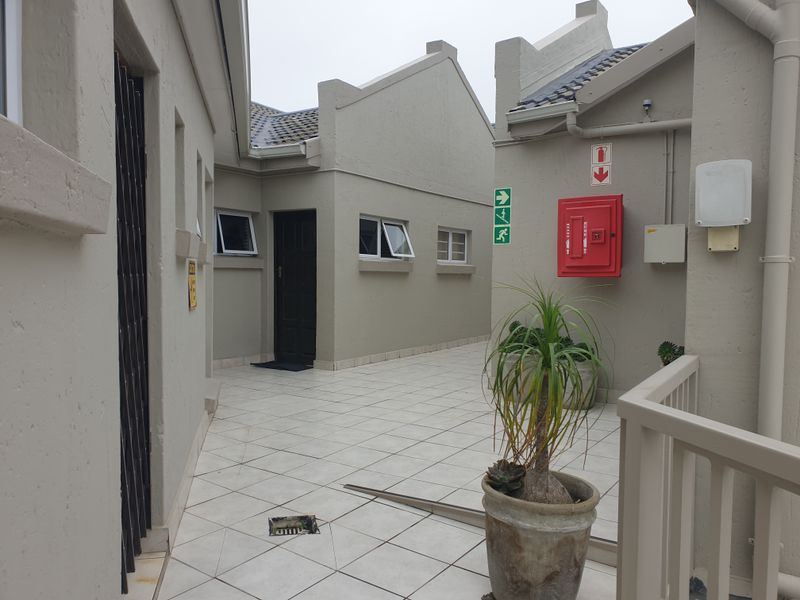 A paved outdoor courtyard area featuring tiled flooring, emergency fire safety equipment, and access points to the apartment building.