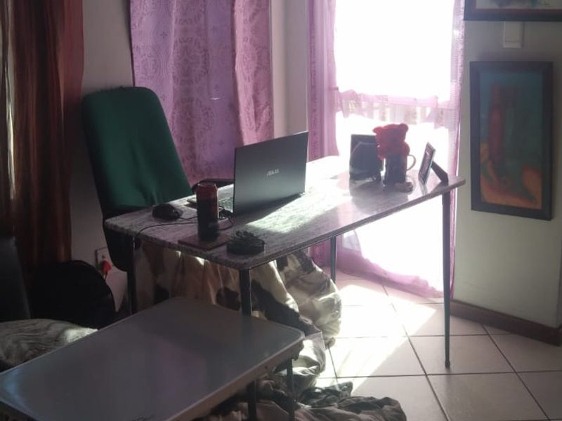 A functional home office space featuring tiled flooring and natural light from a window, suitable for a dedicated workspace.