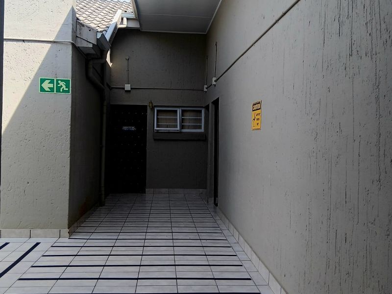 A covered exterior walkway featuring tiled flooring, providing access to the building's rear entrance.