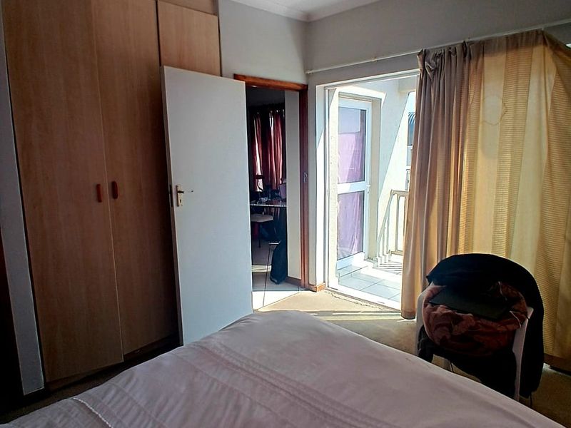 Bedroom featuring built-in wooden cupboards and direct access to a private balcony through a sliding glass door.