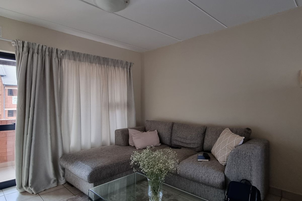 A living room area featuring tiled flooring and a sliding glass door providing access to an outdoor balcony space.