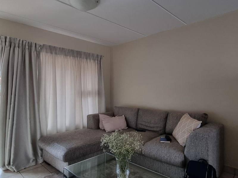 A living room area featuring tiled flooring and a sliding glass door providing access to an outdoor balcony space.