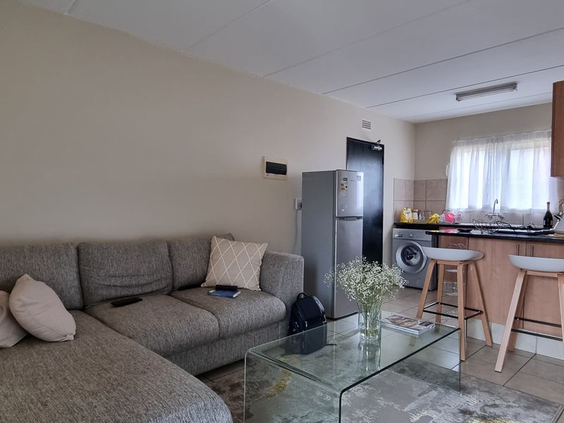 Open-plan living area featuring a functional kitchen with cabinetry, granite countertops, and tiled flooring, seamlessly connected to the lounge space.