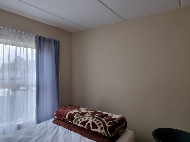 A standard bedroom featuring a built-in wardrobe and a window with installed curtain rails.