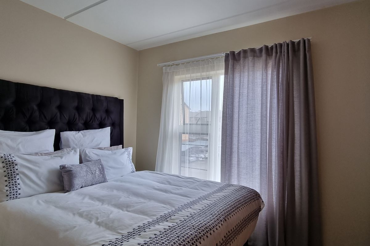 A well-maintained bedroom featuring a built-in wardrobe and a window with installed curtain rails, providing natural light and functional storage space.