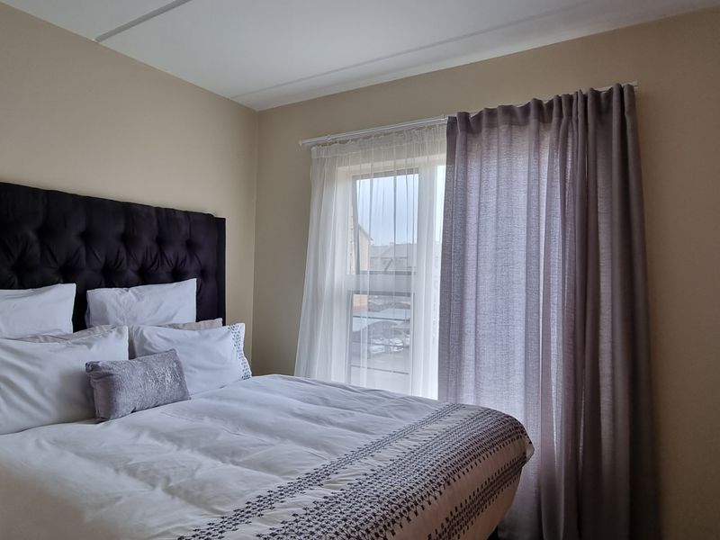 A well-maintained bedroom featuring a built-in wardrobe and a window with installed curtain rails, providing natural light and functional storage space.