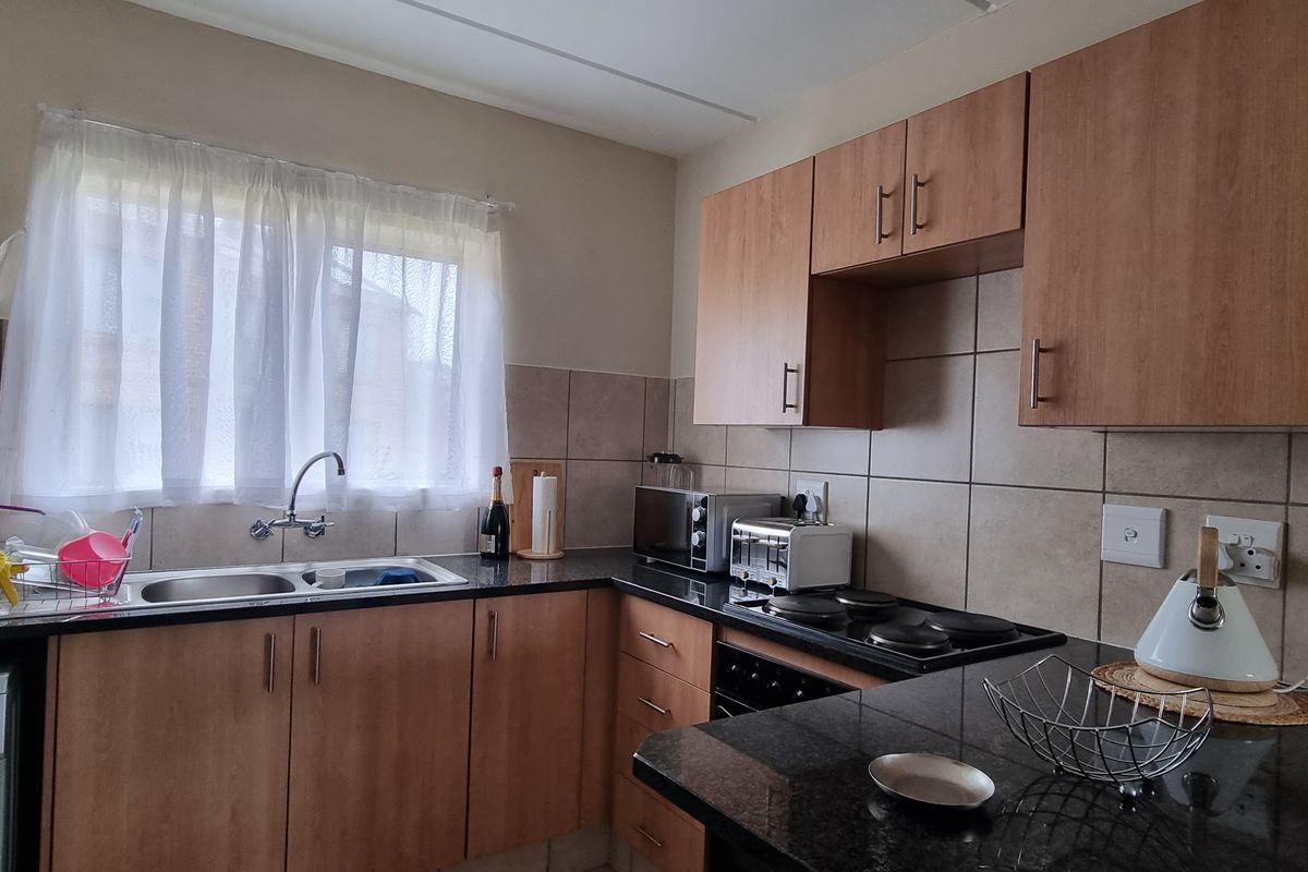A functional kitchen featuring laminate cabinetry, granite countertops, a double basin sink, and built-in electric cooking appliances with tiled backsplash.