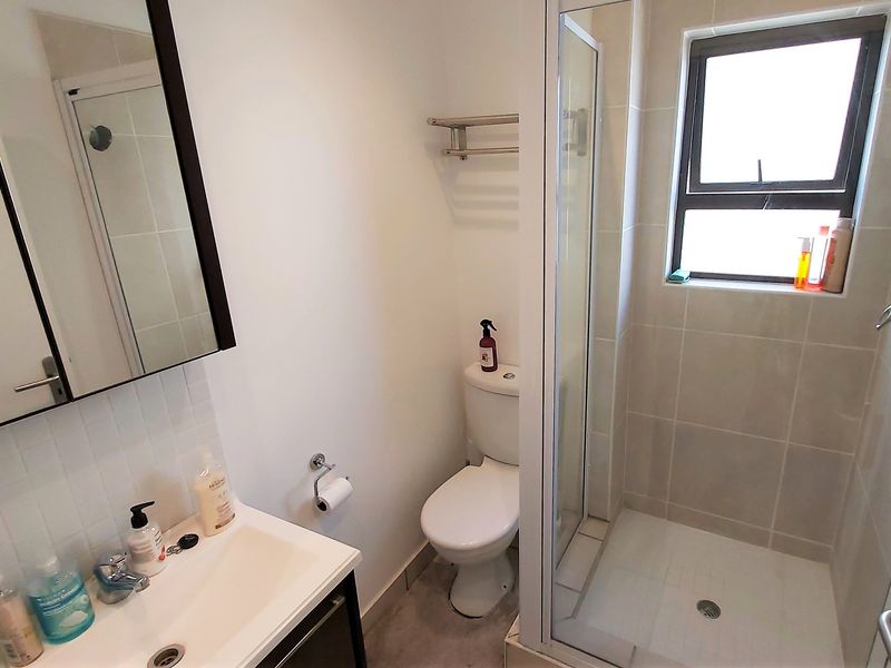 A functional bathroom featuring a vanity with basin, a toilet, and a glass-enclosed shower with tiled finishes.