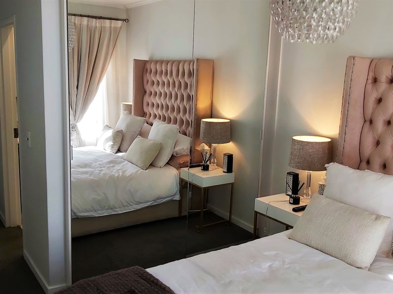 A well-maintained bedroom featuring mirrored built-in cupboards and neutral carpeting, creating a bright and comfortable living space.
