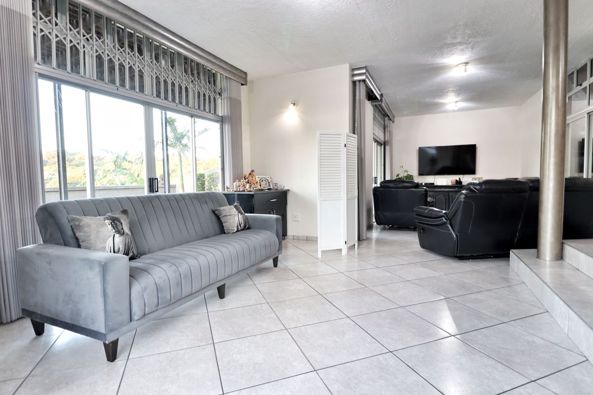 Spacious living area featuring large sliding glass doors with security gates, neutral tiled flooring, and ample natural light.