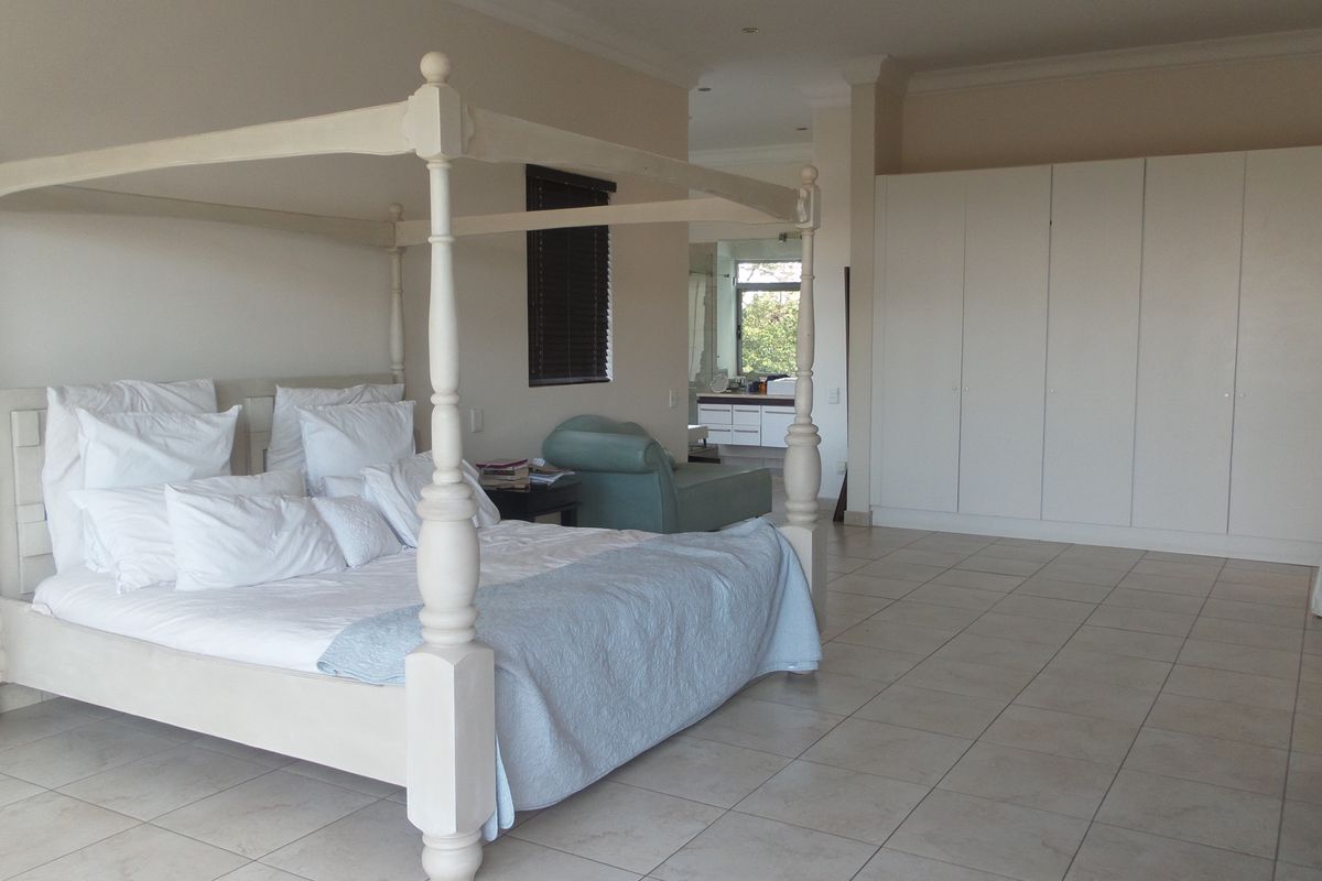 Spacious bedroom featuring neutral tiled flooring, extensive built-in cupboards, and direct access to an en-suite bathroom.