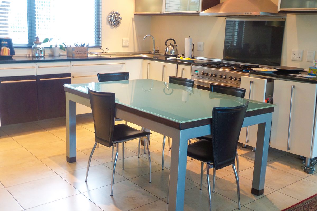 A functional kitchen featuring tiled flooring, modern cabinetry, a gas cooktop with stainless steel extractor, and a built-in oven.