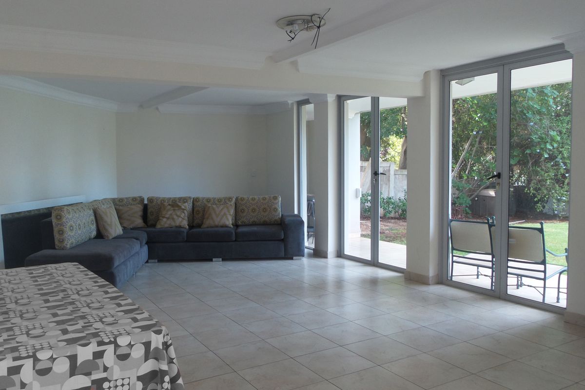Spacious living area featuring neutral tiled flooring, cove cornicing, and large aluminium sliding doors providing direct access to the garden.