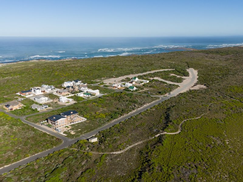 Aerial view of a coastal residential development featuring paved roads and surrounding natural vegetation with ocean views.