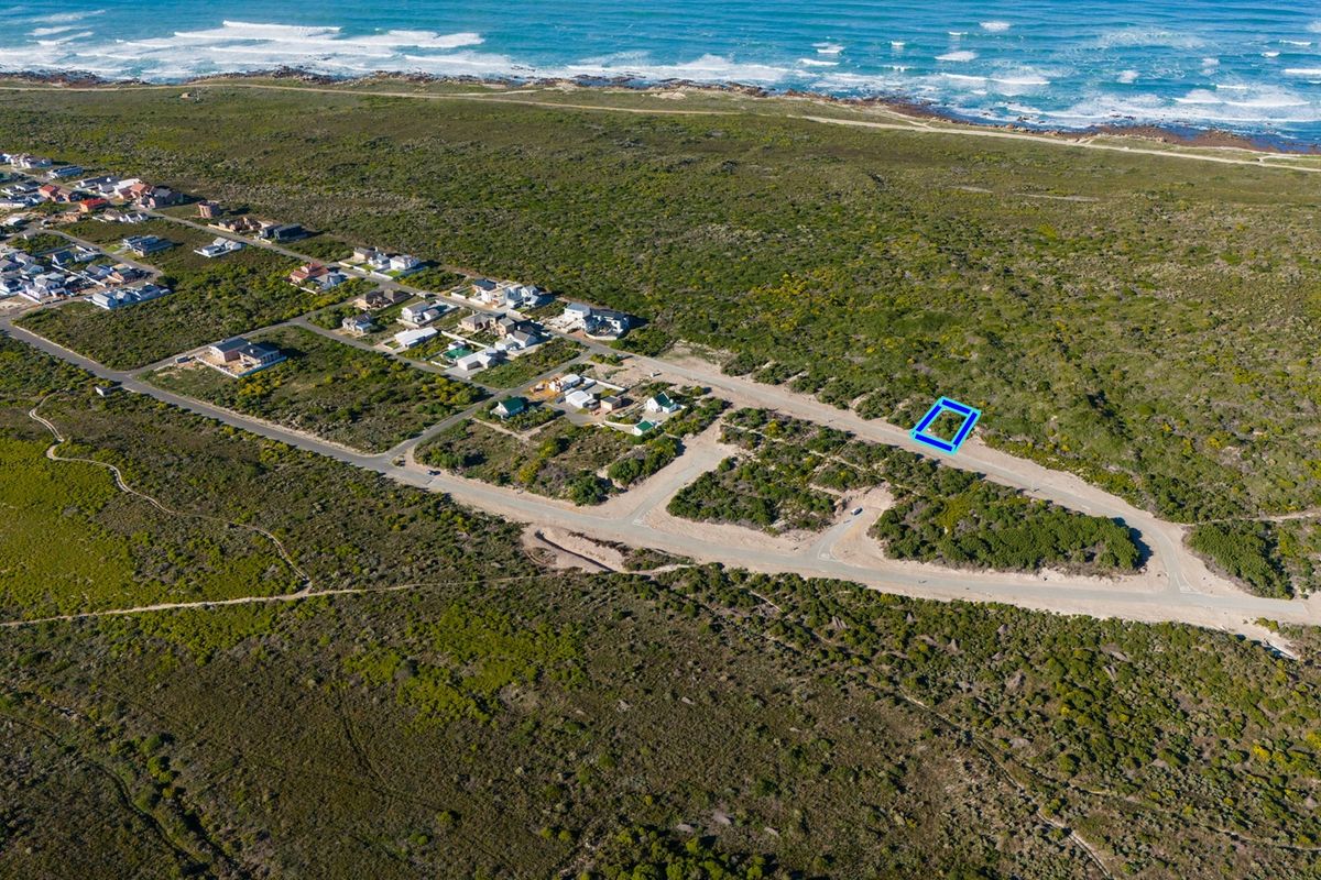 An aerial view of a vacant residential plot situated in a coastal development, highlighting its proximity to the ocean and local road infrastructure.