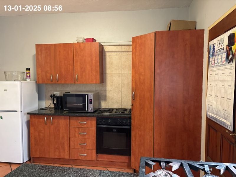 A functional kitchen featuring wooden cabinetry, granite countertops, a built-in oven, and a hob with a tiled backsplash.