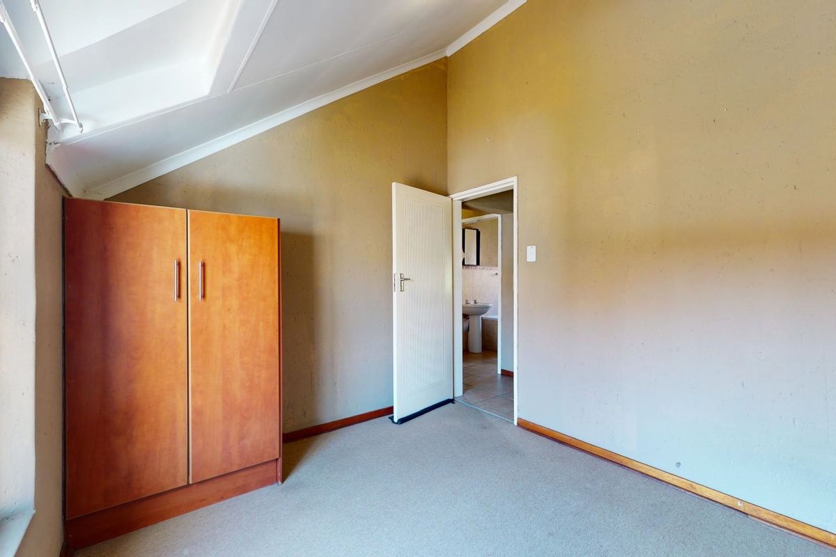 A bedroom featuring a sloped ceiling, carpeted flooring, and direct access to an en-suite bathroom.