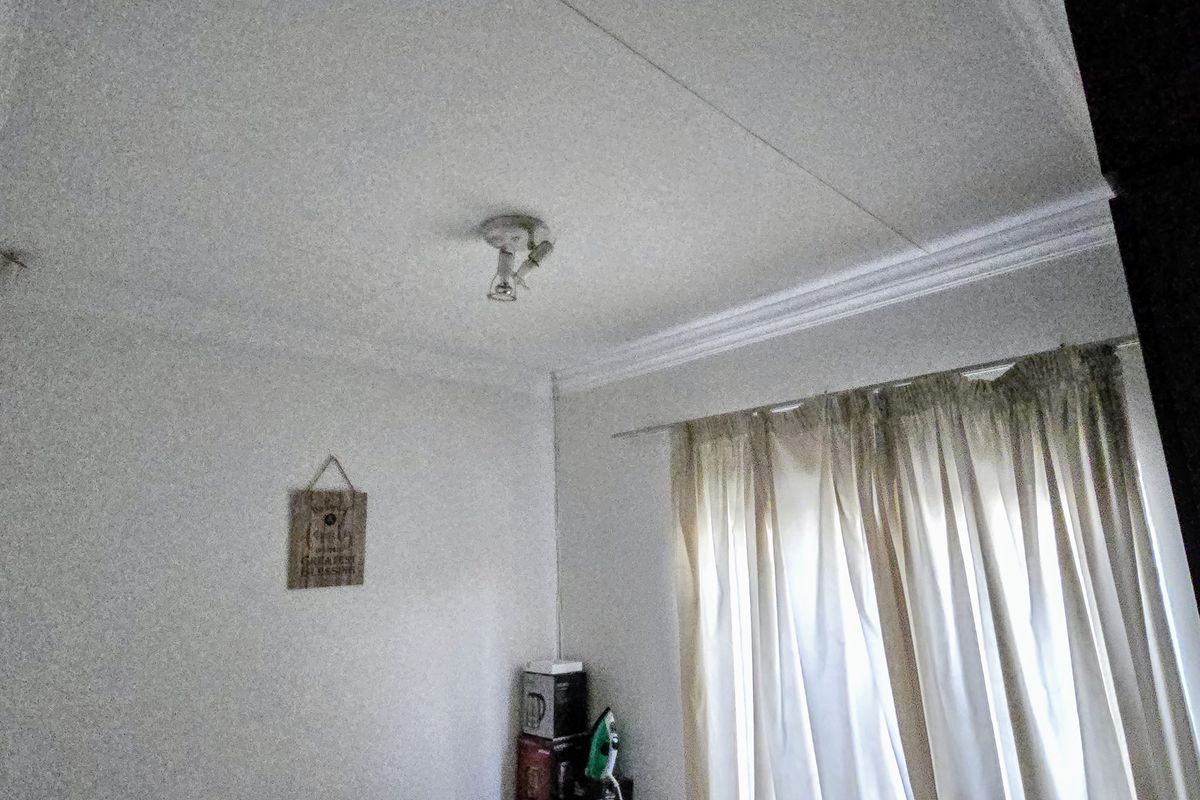 A simple bedroom space featuring decorative ceiling cornicing and a curtain rail, providing a neutral foundation for interior design updates.