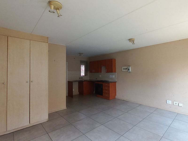 Open plan living area featuring tiled flooring, built-in storage cupboards, and a functional kitchen with built-in cabinetry and oven.