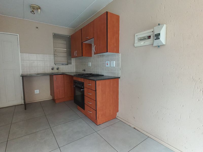 A functional kitchen featuring built-in cabinetry, a hob, an oven, and tiled flooring. The space is currently vacant and ready for updates.
