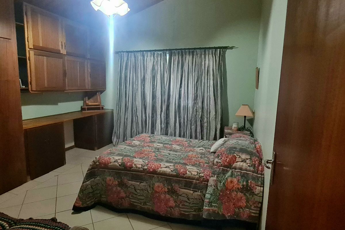 A bedroom featuring built-in wooden cabinetry, a desk area, tiled flooring, and a vaulted ceiling, offering a functional and traditional layout.