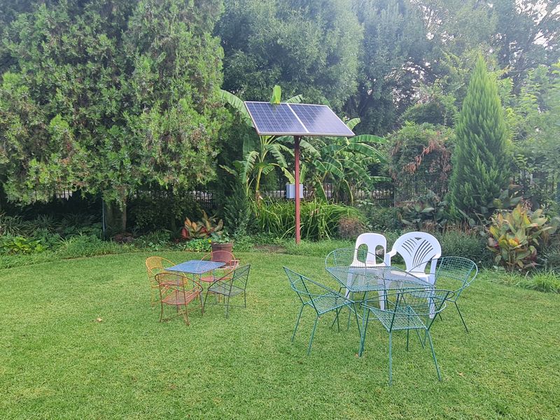A well-maintained garden area featuring a standalone solar panel array and secure metal perimeter fencing.