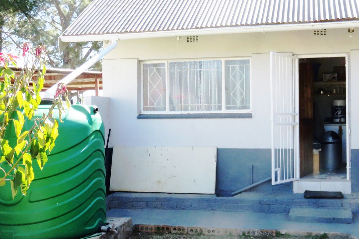 Rear exterior view of the house featuring a corrugated metal roof, water storage tank, and direct access to the utility area.