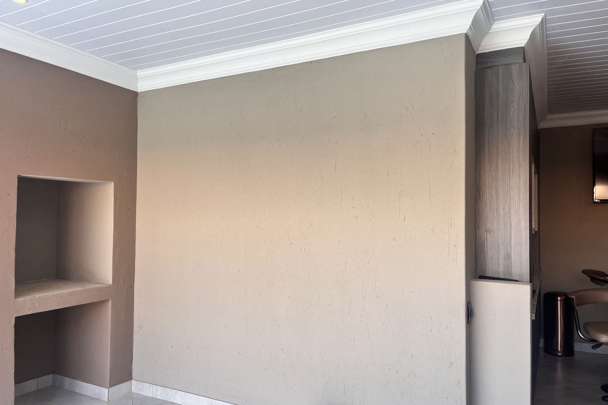 A spacious living area featuring a built-in wall niche, decorative crown molding, and a classic tongue and groove ceiling finish.