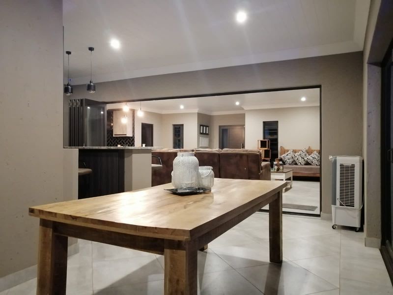 Spacious open-plan living area featuring tiled floors, recessed lighting, and a modern kitchen island, seamlessly connecting to the adjacent living space.