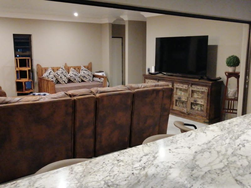 Open plan living area featuring a granite kitchen island countertop and recessed downlighting, creating a functional and connected space.