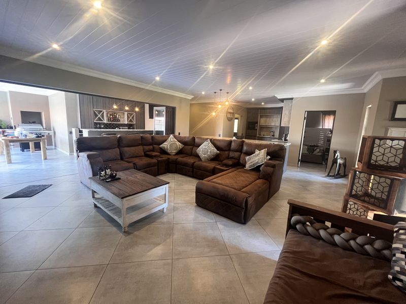 Spacious open-plan living area featuring tiled floors, recessed lighting, and a seamless flow between the lounge, bar, and kitchen spaces.