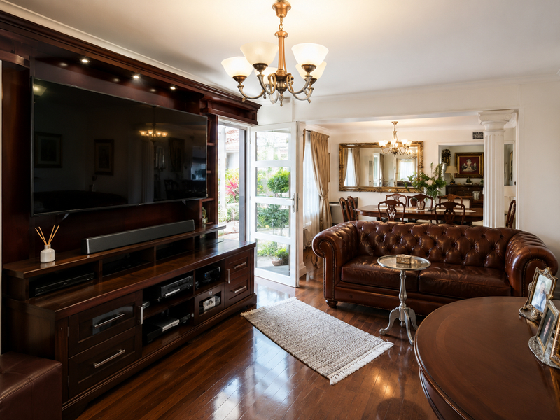 Spacious open-plan living and dining area featuring rich hardwood flooring, custom built-in cabinetry, and elegant architectural details with direct access to the garden.