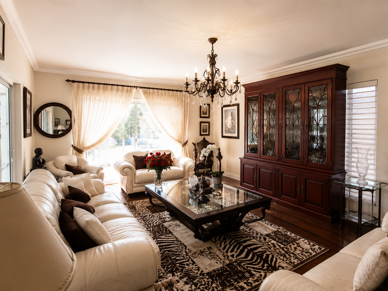 A well-maintained living room featuring hardwood flooring, crown molding, a large built-in display cabinet, and sliding glass doors providing natural light.