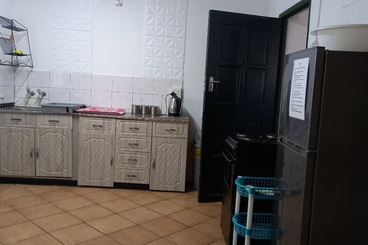 A functional kitchen featuring tiled flooring, built-in cabinetry with countertop space, and a tiled splashback area.