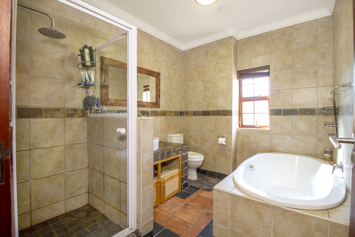 A spacious bathroom featuring a walk-in shower, a built-in bathtub, and a vanity unit with tiled finishes throughout.