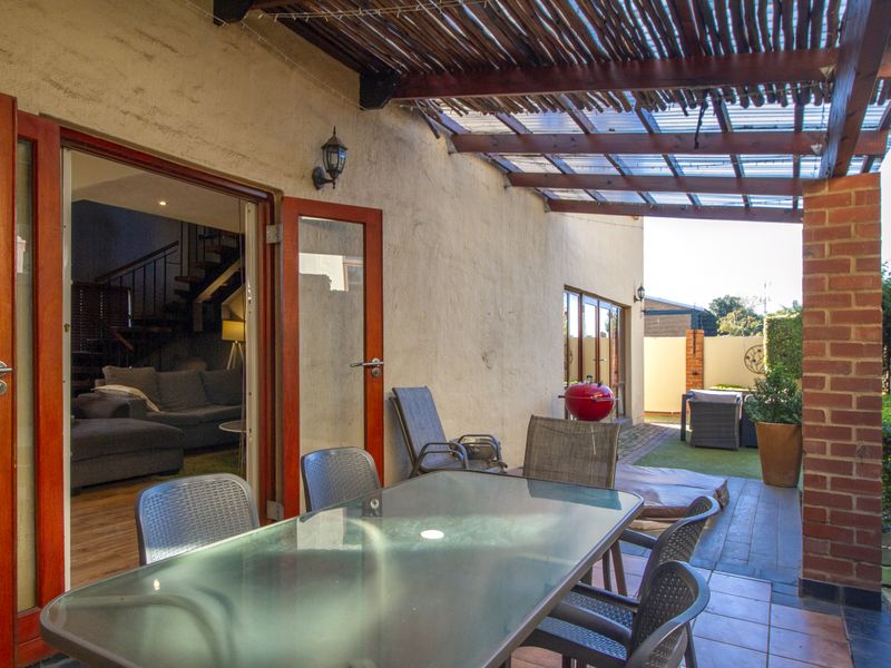 Covered outdoor patio area featuring a timber pergola, tiled flooring, and direct access to the interior living space through double glass doors.