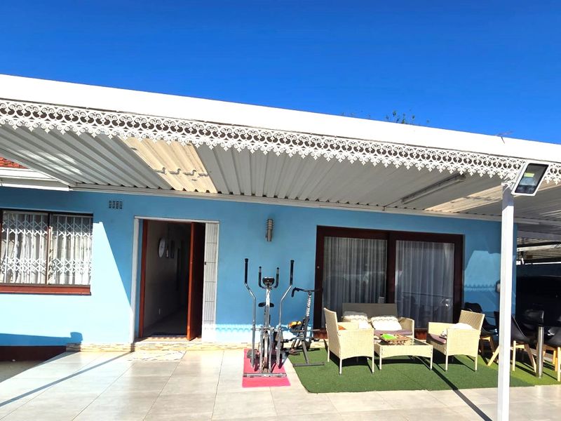 A covered patio area featuring tiled flooring, decorative metal trim, and direct access to the home through sliding glass doors and a security gate.