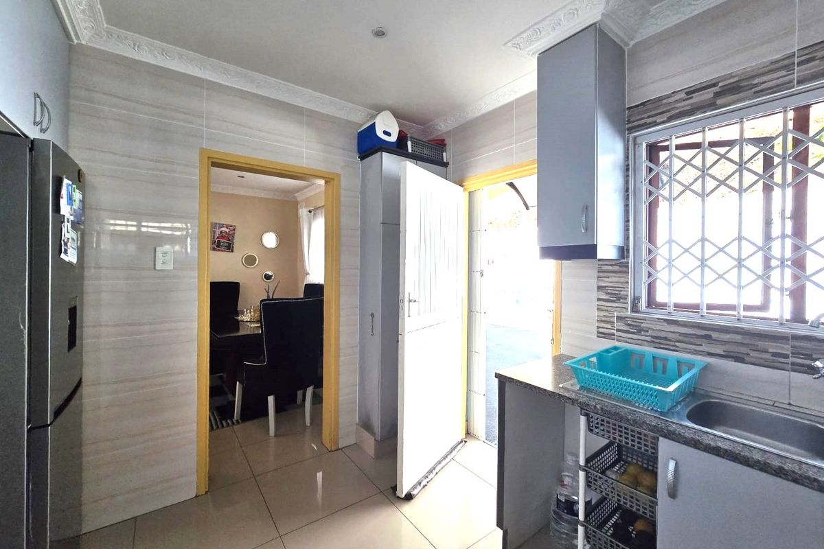 Functional kitchen featuring tiled walls and flooring, granite countertops, built-in cabinetry, and direct access to the exterior via a security gate.