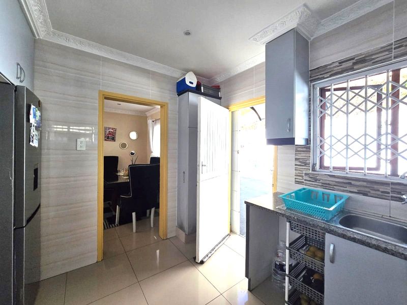 Functional kitchen featuring tiled walls and flooring, granite countertops, built-in cabinetry, and direct access to the exterior via a security gate.
