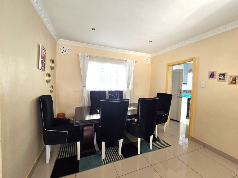 A dining room featuring tiled flooring, decorative ceiling cornicing, and recessed lighting, with a doorway leading to an adjacent kitchen area.