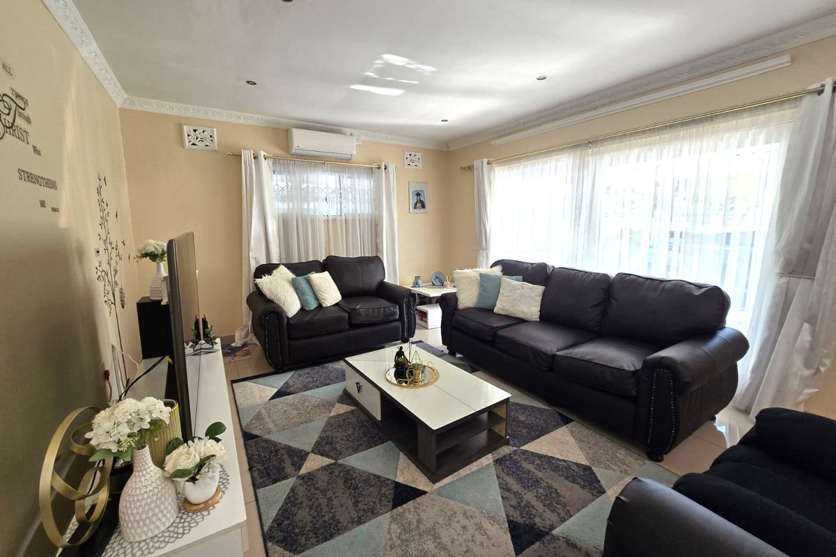 A well-maintained living room featuring tiled flooring, recessed downlighting, decorative ceiling cornices, and a wall-mounted split-system air conditioner.