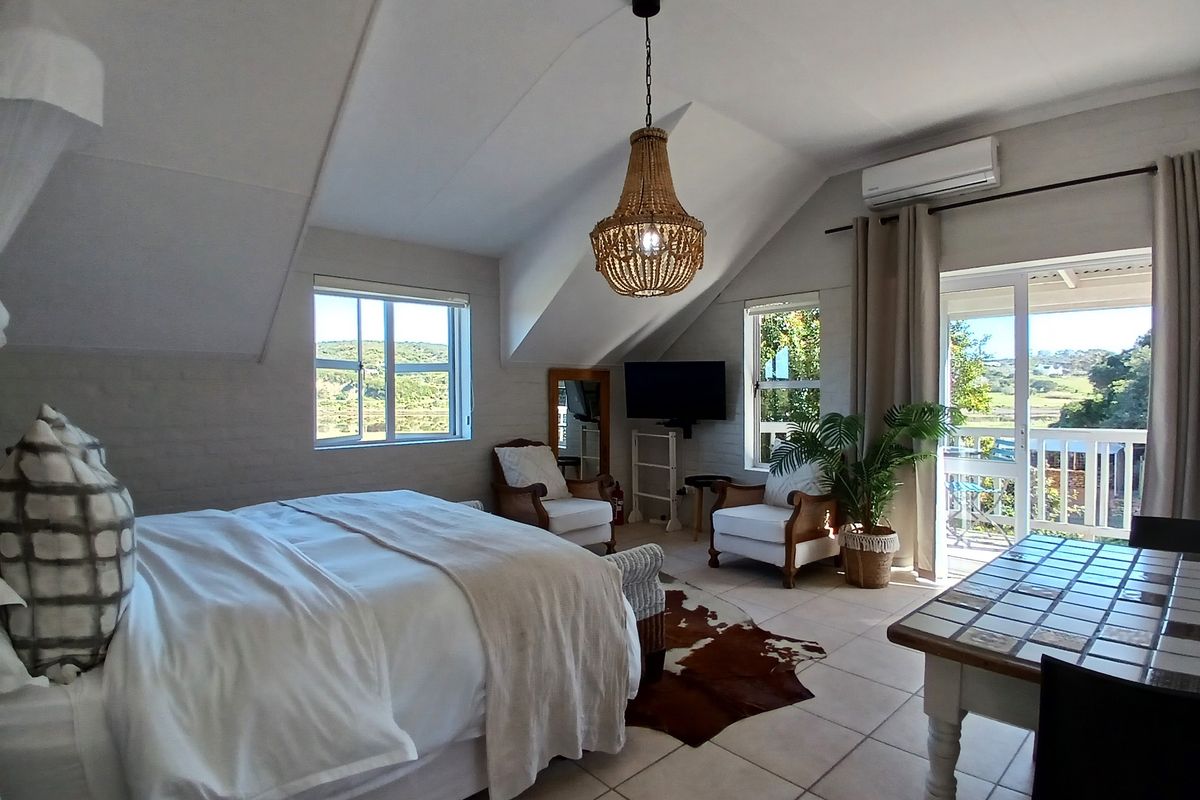Spacious bedroom featuring vaulted ceilings, tiled flooring, split-system air conditioning, and direct access to a private balcony with scenic views.