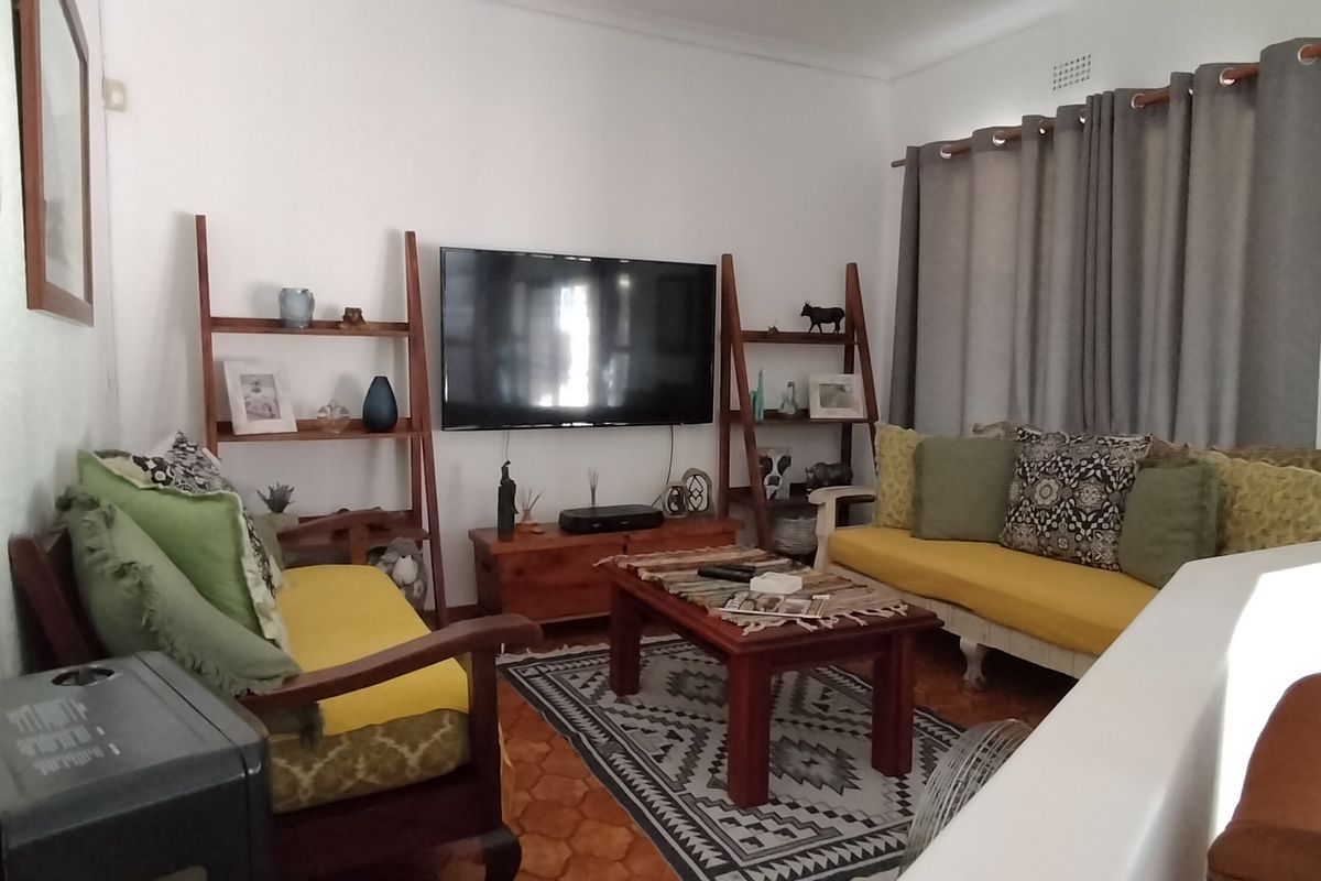 A comfortable living room featuring tiled flooring, coving, and a wall-mounted television setup, providing a functional and inviting space for relaxation.