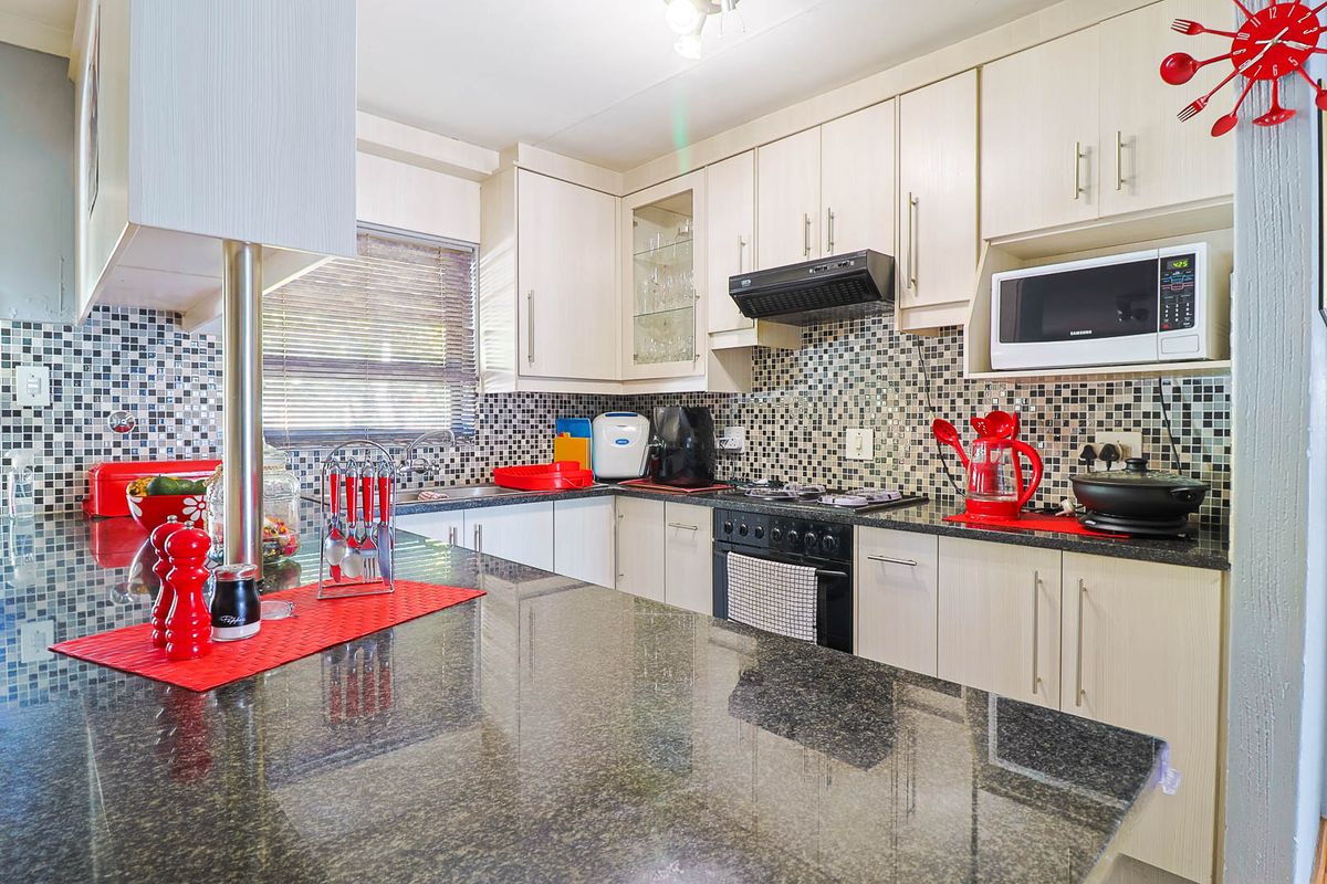 A functional kitchen featuring granite countertops, mosaic tile backsplash, built-in oven, extractor fan, and ample laminate cabinetry for storage.