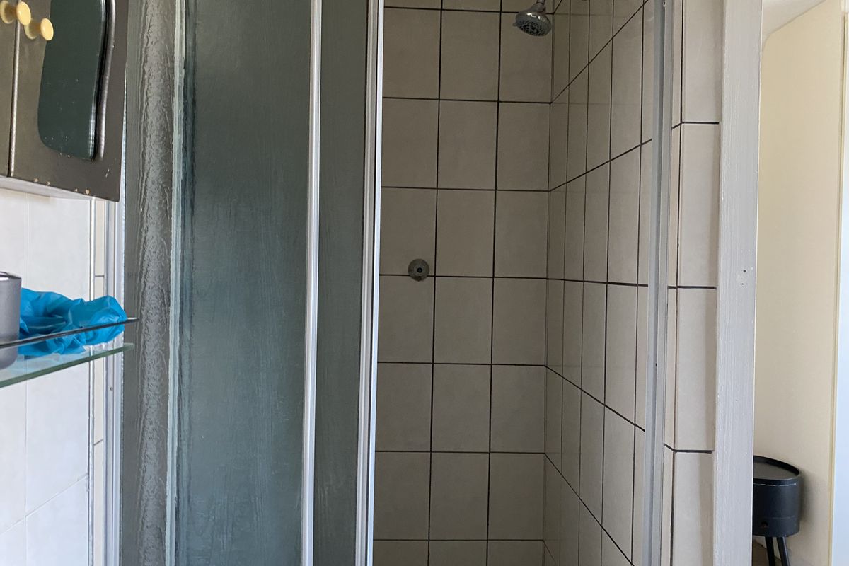 A functional bathroom shower stall featuring tiled walls and a standard shower head fixture.