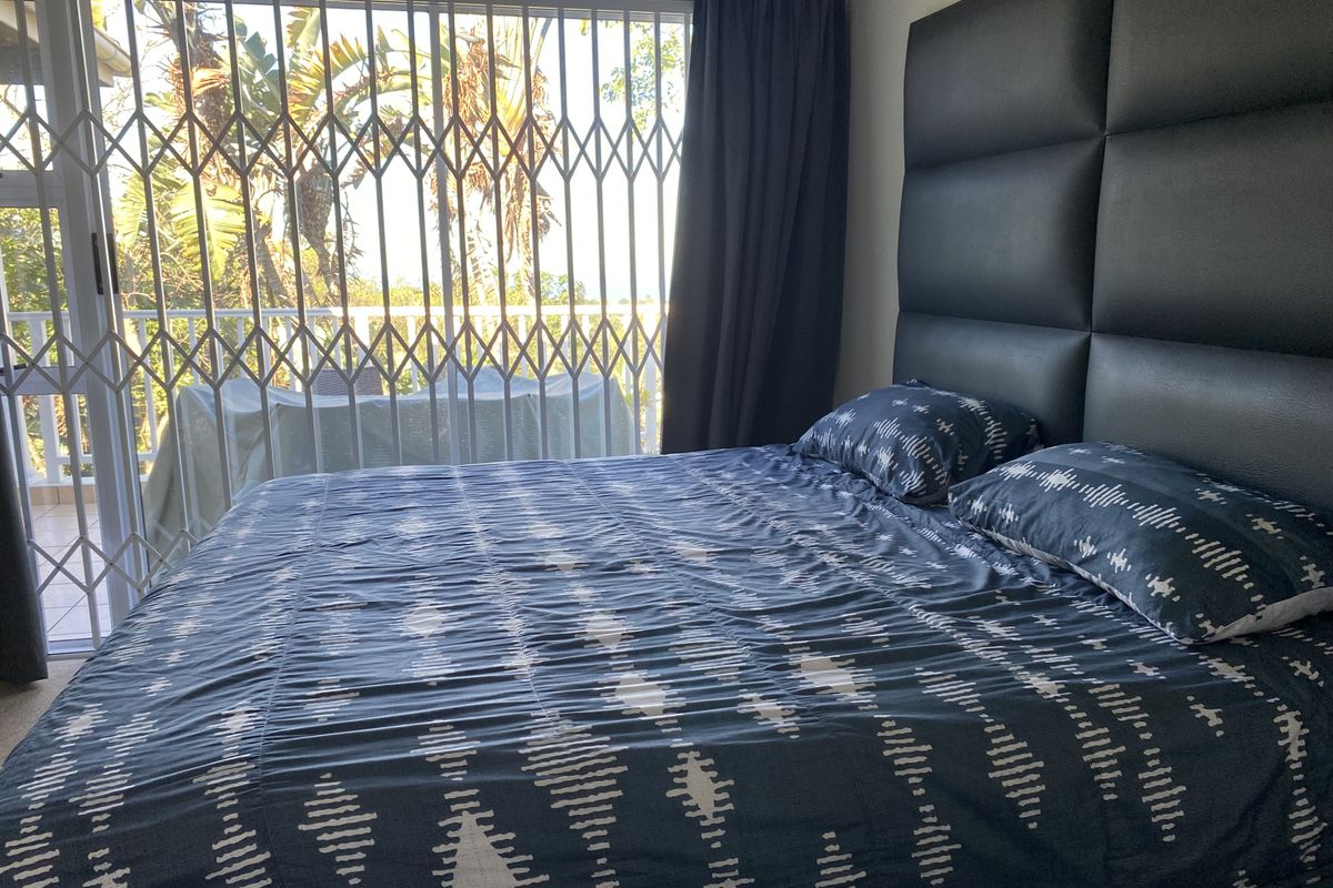 A bedroom featuring a sliding glass door with a security gate providing access to an outdoor balcony area.