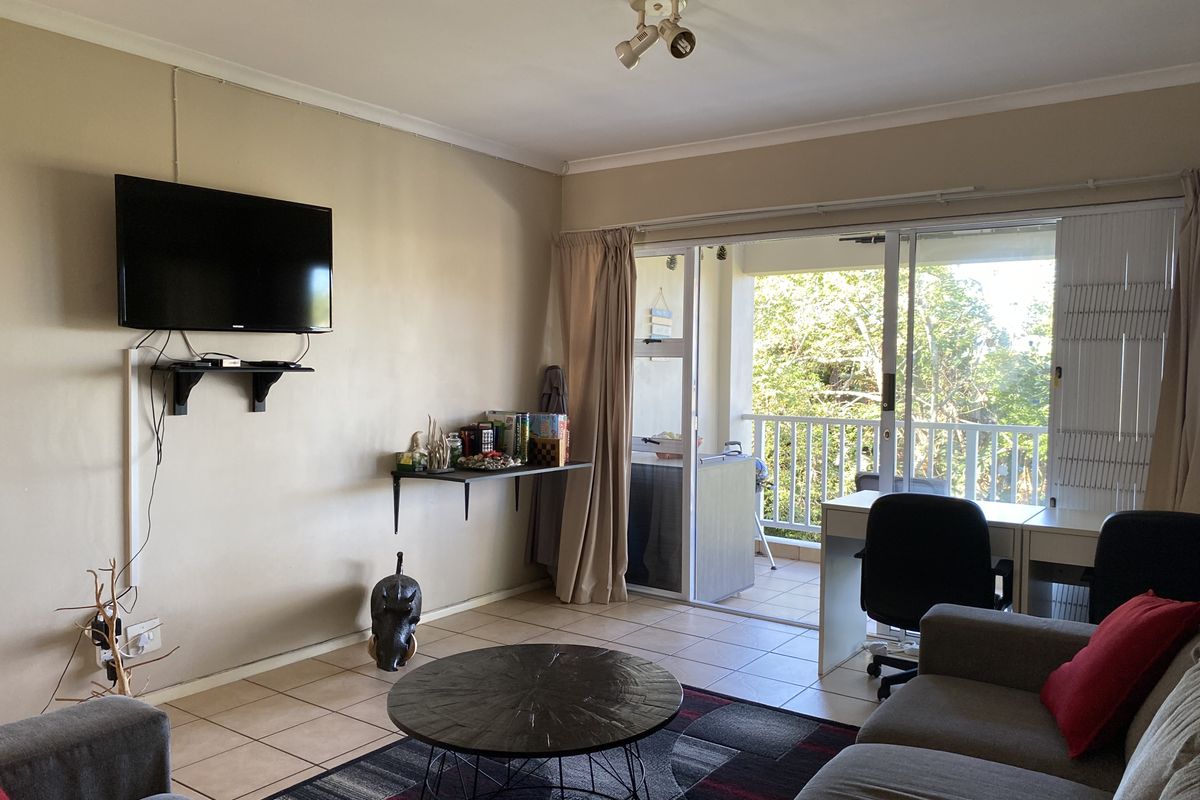 Living room featuring tiled flooring and sliding glass doors leading to a balcony, providing natural light and access to outdoor space.